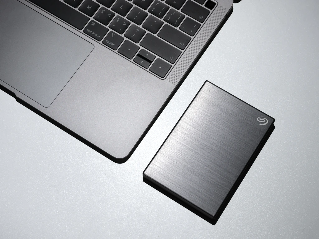 Bild von einer externen Festplatte neben einem MacBook.